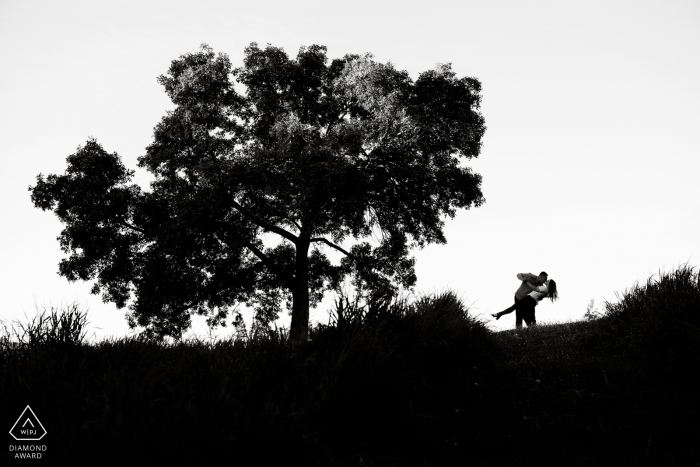 an Edmonton, Alberta Couple dips under tree during their black and white engagement photoshoot