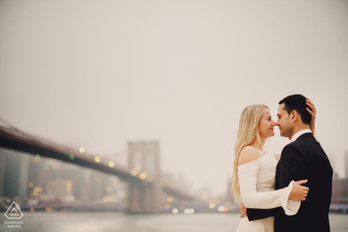 Pareja de Nueva York besándose con Nueva York de fondo durante su sesión de fotos de retrato de compromiso