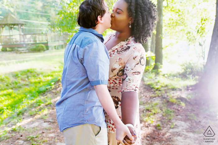 um beijo de casal em Pine Lake, GA durante sua sessão de fotos ao ar livre antes do casamento