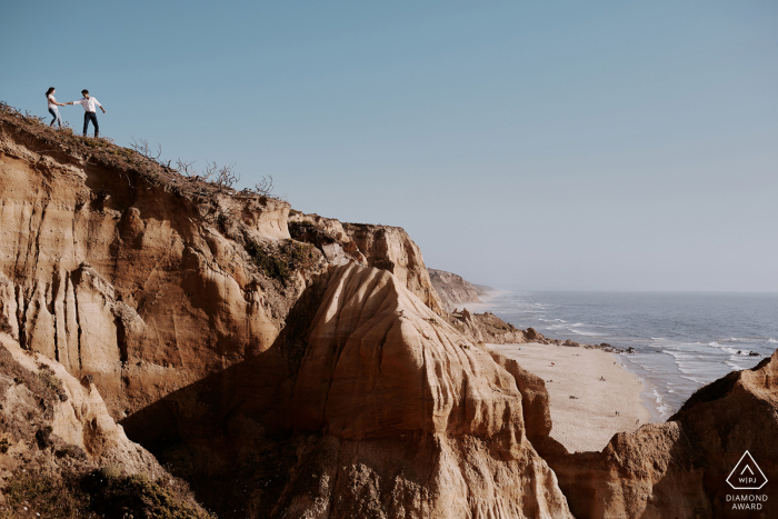 a Portugal Bride and groom playing on the top of a hillside overlooking a beautiful beach in Vale Furado, Nazaré