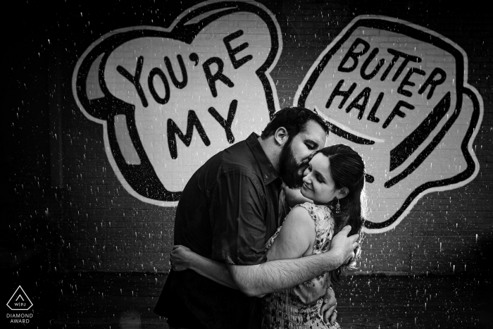 portrait of a couple holding each other in front of a mural Austin TX engagement portrait of a couple holding each other in front of a mural
