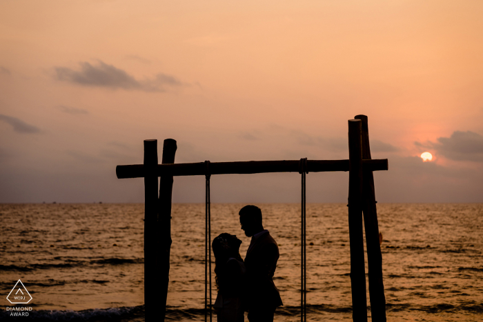 Fotos de noivado da Ilha de Phu Quoc com a silhueta de um casal contra o pôr do sol e a água