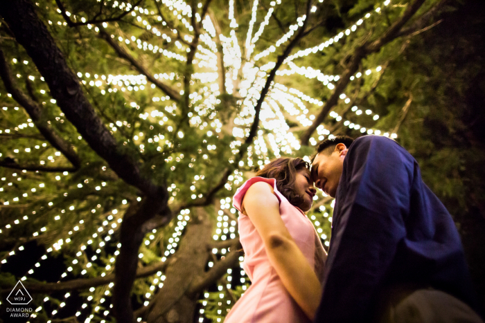 Los Gatos Love under Christmas tree lights during engagement photo session