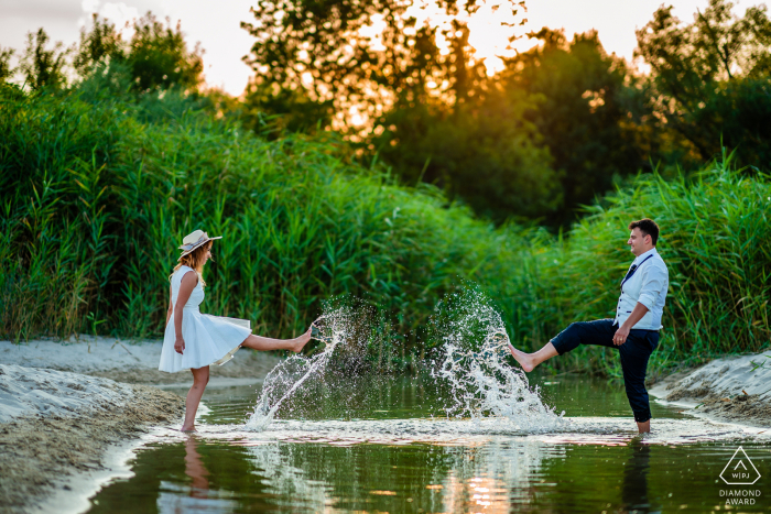 Albena, Bulgária casal se diverte chutando água no lago.