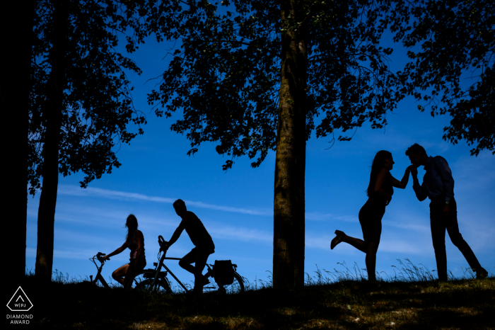 A silhouette portrait of a couple with a bicycling couple riding by in De Klinge A silhouette portrait of a couple with a bicycling couple riding by in De Klinge