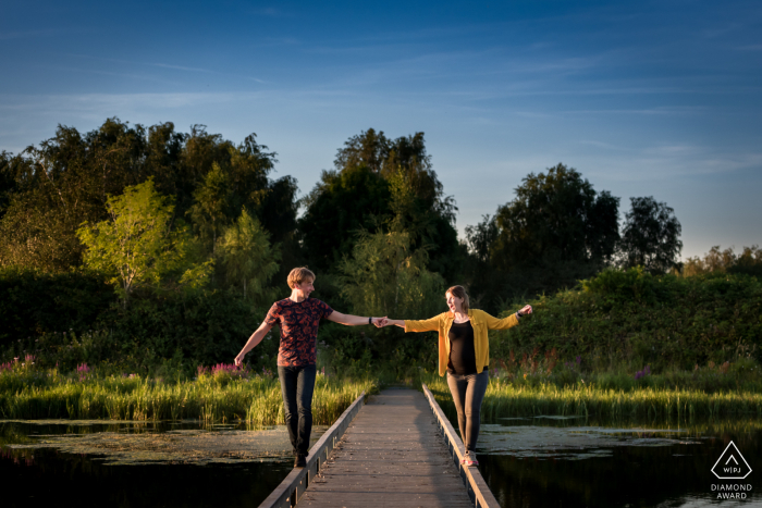 Dintelse Gorzen, De Heen couple walking about a bridge, both on the edge, during image session Dintelse Gorzen, De Heen couple walking about a bridge, both on the edge, so they can say we trust each other
