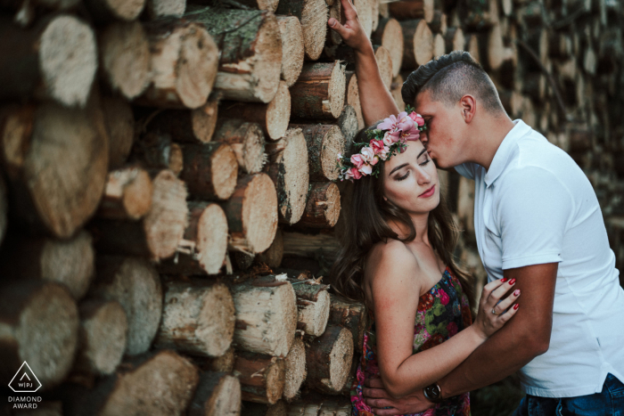 Pobłocie Wielkie Pareja junto contra una pared de leña cortada y apilada durante la sesión de fotos de compromiso