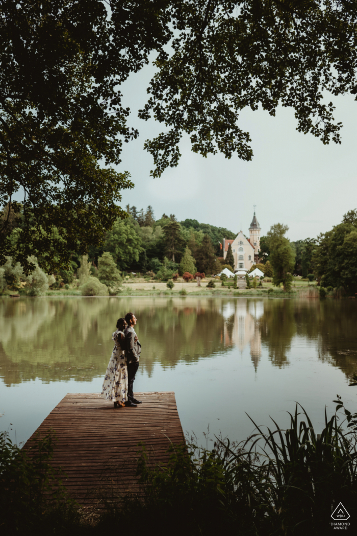 Retratos de compromiso de Pałac Bursztynowy En el lado del lago con un bonito muelle y árboles