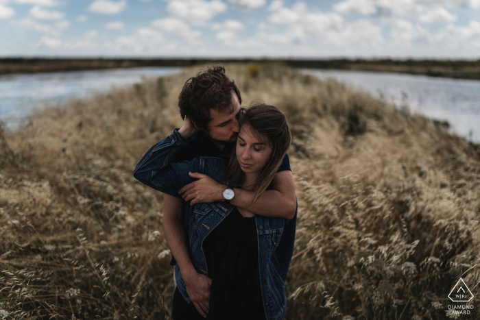 a France couple is posing for images in an embrace in the grass surrounded by water in Noirmoutiers a France couple is posing in an embrace in the grass surrounded by water in Noirmoutiers