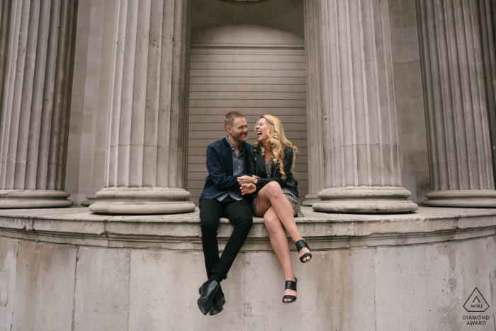 UK seated couple engagement photography in the City of London, England sitting upon some architecture