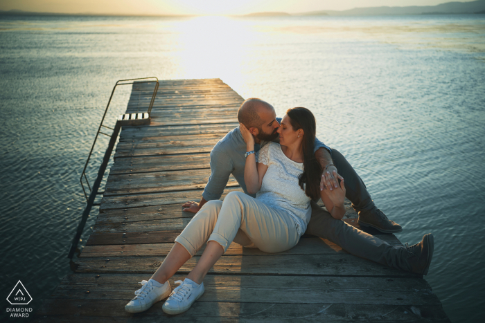 Retratos de pareja del lago Trasimeno con los dos solos en el muelle de madera al atardecer junto al agua Retratos de pareja del lago Trasimeno con los dos solos en el muelle de madera al atardecer junto al agua