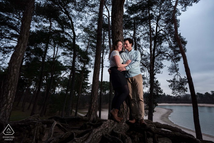 This newly engaged couple is standing on the roots of tree with an incredible view at the Henschotemeer