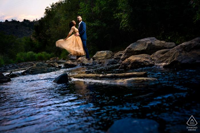 Casal de noivos olha rio abaixo durante retratos da sessão de noivado no Parque Lair o 'the Bear em Idledale, CO