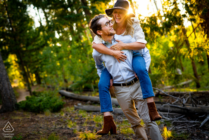 El futuro novio le da a su futura novia un paseo en caballito durante su sesión de compromiso en Meyer Ranch Park en Morrison, CO