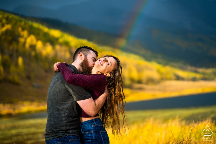 Pareja abrazada durante una inesperada tormenta vespertina en su sesión de compromiso en Piney River Ranch en Vail, CO