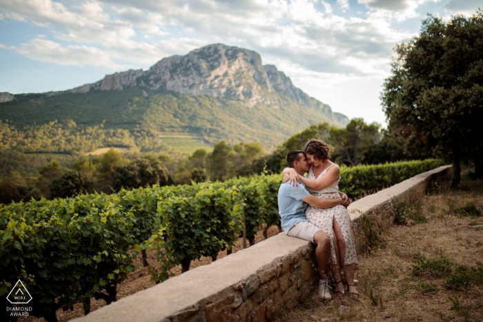 FR pre wedding portrait session with engaged lovers at Domaine de L'Hortus South of France with a couple sitting on a low wall