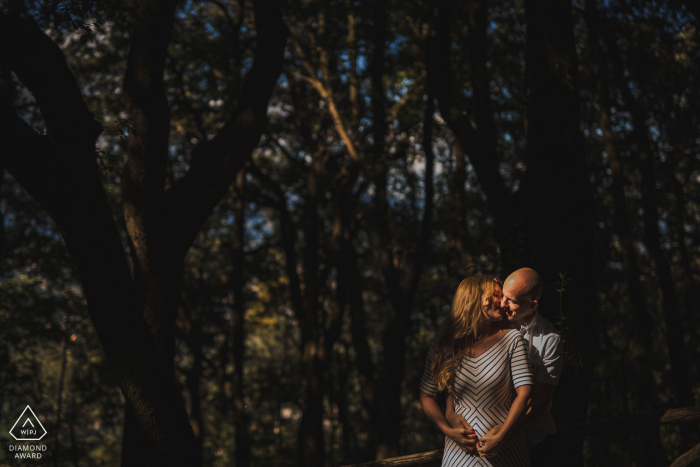 IT-Porträtsitzung vor der Hochzeit mit engagierten Liebhabern im Schatten der Bäume in Spoleto - Italien mit dem Paar im Sonnenfleck