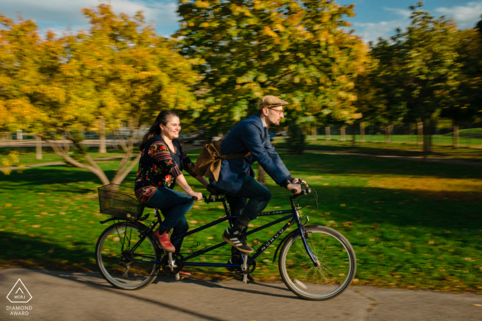 Fotografía previa a la boda y el compromiso de Canadá en Parc Laurier, Montreal, Quebec con una pareja que viajaba en una bicicleta tándem a través de un parque; se conocieron cuando él era un mensajero en bicicleta e hicieron una entrega en su oficina.