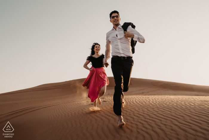 Servizio fotografico di fidanzamento nelle sabbie degli Emirati Arabi Uniti con una divertente coppia di innamorati nel deserto di Dubai