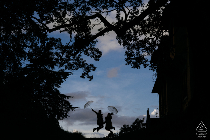 Vietnam silhouette engagement portrait with a posed couple jumping with umbrellas in Dalat