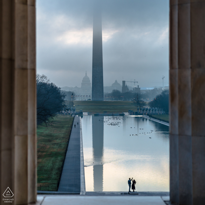 DC przedślubna sesja portretowa zaręczonych kochanków w Lincoln Memorial DC z widokiem od wewnątrz, patrząc na odbijający się basen i wirującą parę