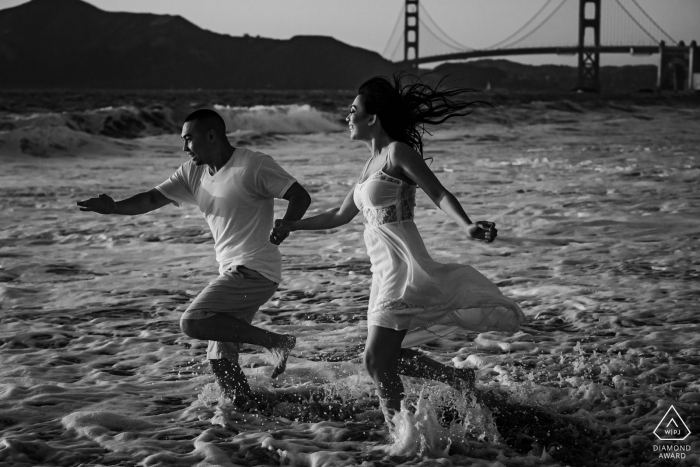 Baker Beach, San Francisco, California, pareja al atardecer correr en la playa durante una sesión de fotos antes del matrimonio