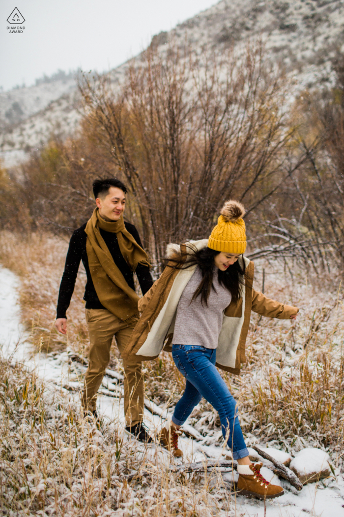 Lair O Bear Park Pareja caminando por la nieve durante una sesión de fotos de compromiso de invierno antes del matrimonio