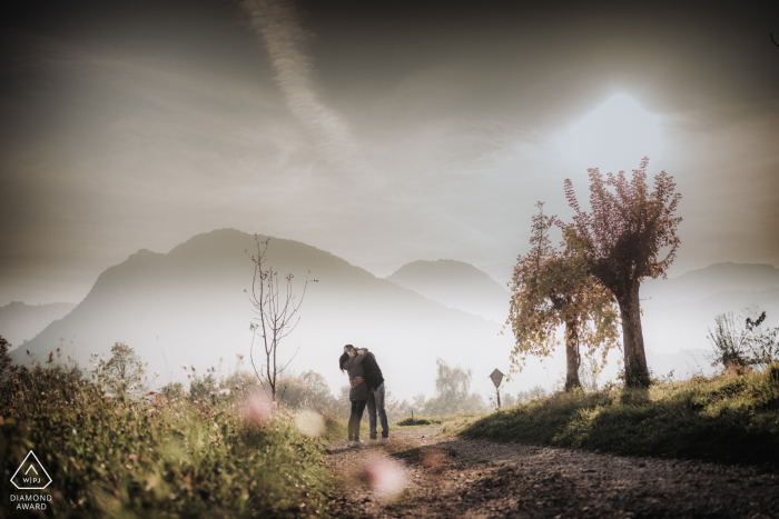 Schio, Vicenza, Italia micro sessione fotografica di montagna all'aperto prima del giorno del matrimonio di una coppia che si bacia davanti ad alcune montagne