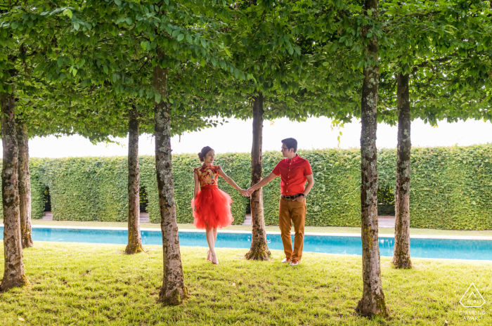 Chateau du Tertre, Bordeaux, Francia sessione di foto al di fuori della foresta prima del giorno delle nozze che mostra una coppia in rosso in mezzo agli alberi