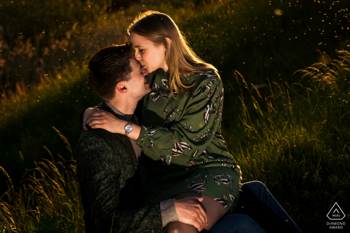 Mini sesión de fotos en el centro de Willemstad antes del día de la boda - pareja en un campo de hierba con un beso en la bonita puesta de sol