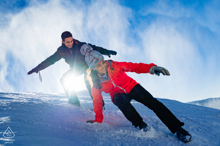 Sessão de fotos do casal na montanha Sierra Nevada, Granada antes do dia do casamento, com o casal deslizando por uma colina íngreme de neve no inverno