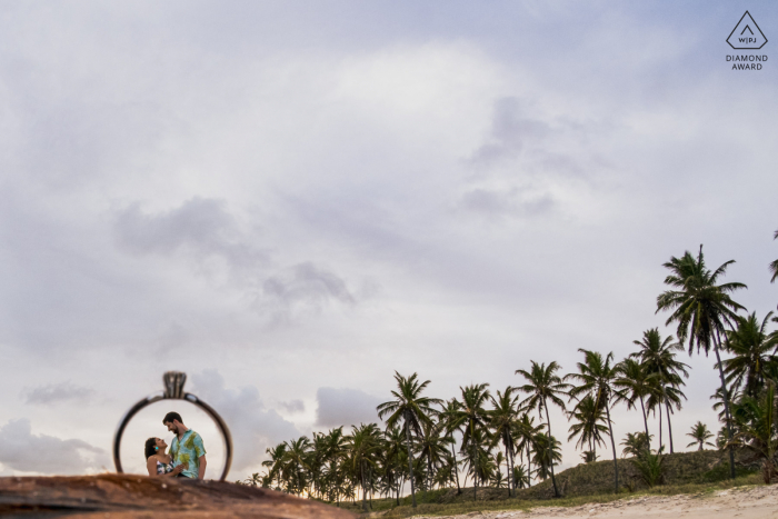 Marechal Deodoro mini beach couple photography session before the wedding day with an image shot through the engagement ring in the sand