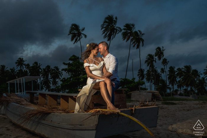 Séance de photographie sur la mini plage Maragogi avant le mariage avec le couple assis sur un petit bateau