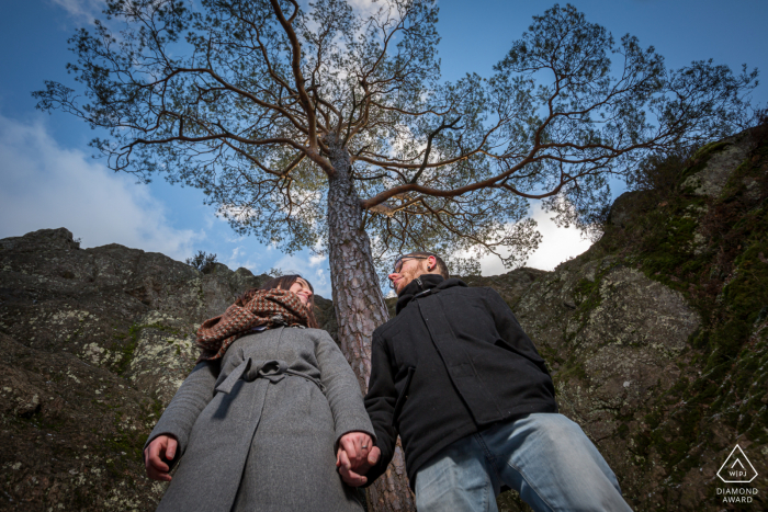 Sessão de fotos ao ar livre do casal Rocher du Falkenstein antes do dia do casamento, mostrando um ângulo de câmera baixo com uma árvore solitária centralizada