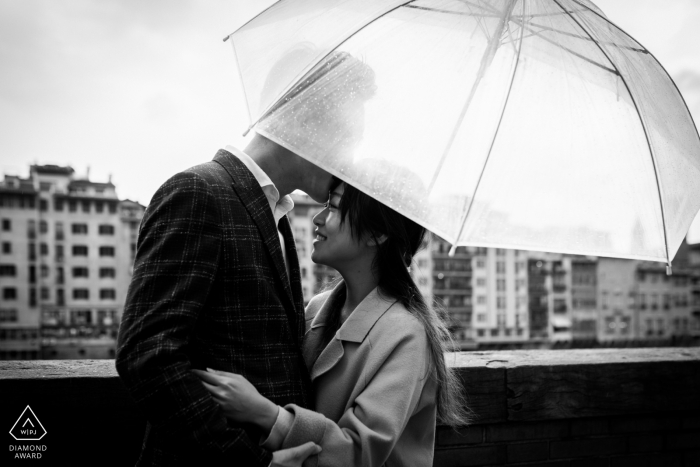 Lungarno Corsini, mini sesión de fotos urbanas de Florencia antes del día de la boda bajo la lluvia mientras la pareja se besa bajo el paraguas