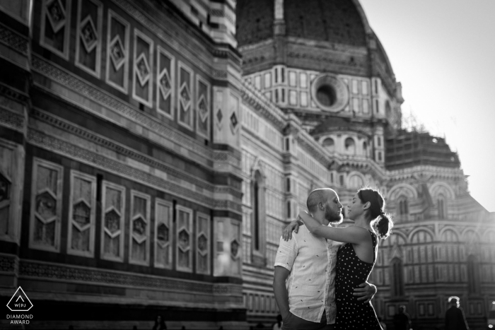 Piazza Duomo, Florence mini urban pic shoot before the wedding day while the couple is hugging in the sunlight by the buildings