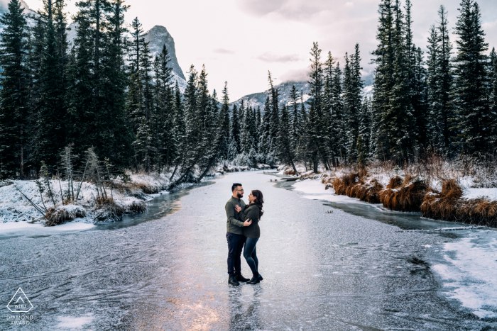 Canmore, AB, Canadá fora da sessão de fotos de inverno antes do dia do casamento No riacho congelado