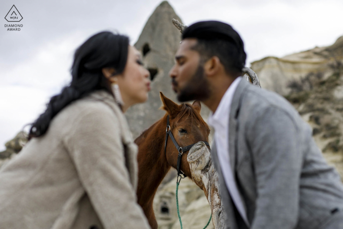 Sessão de fotos de mini casal na Capadócia, Turquia antes do dia do casamento com um cavalo amarrado a um poste