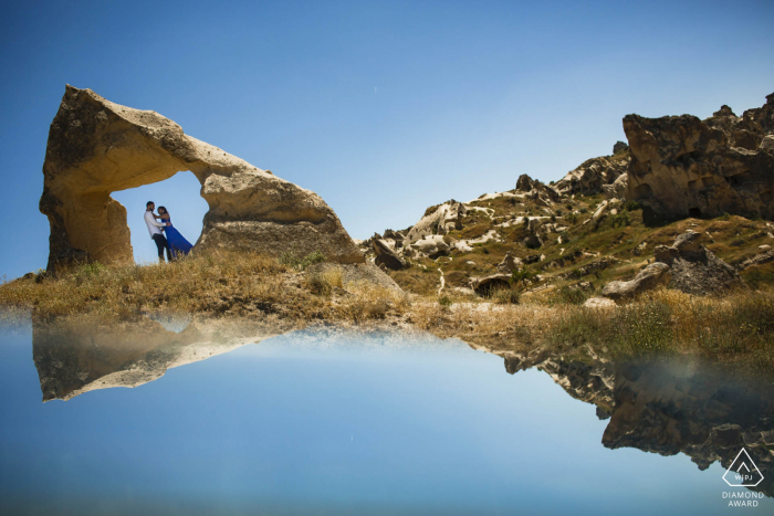 Capadocia, Turquía mini sesión de fotos de pareja antes del día de la boda con un reflejo del amanecer en el espejo en las rocas