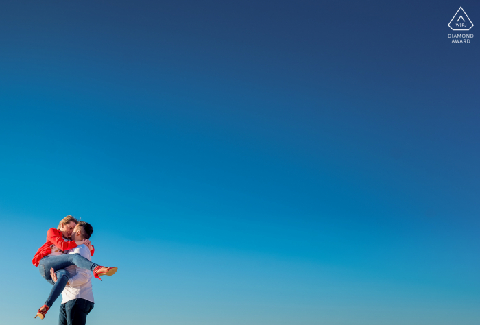 Sessão de fotos de mini casal em Almeria, Espanha antes do dia do casamento, com diversão e amor sob um céu azul brilhante e mínimo