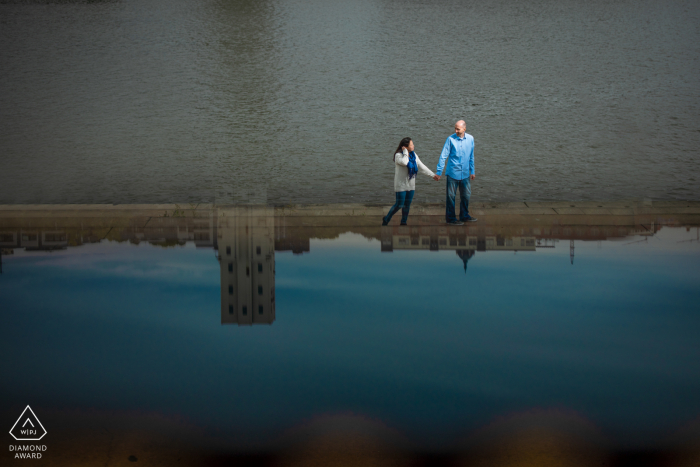 St Paul reflection portrait by the water in MN with a Couple walking near the water in the city 