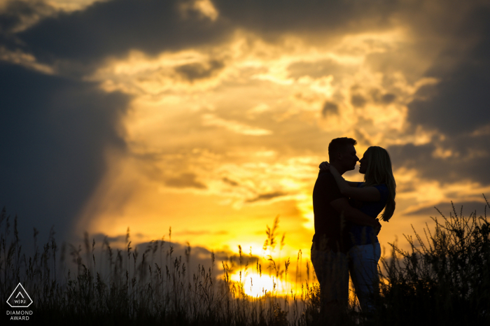 Sessão de retrato de casal em silhueta ao pôr do sol de Fort Collins em uma colina gramada