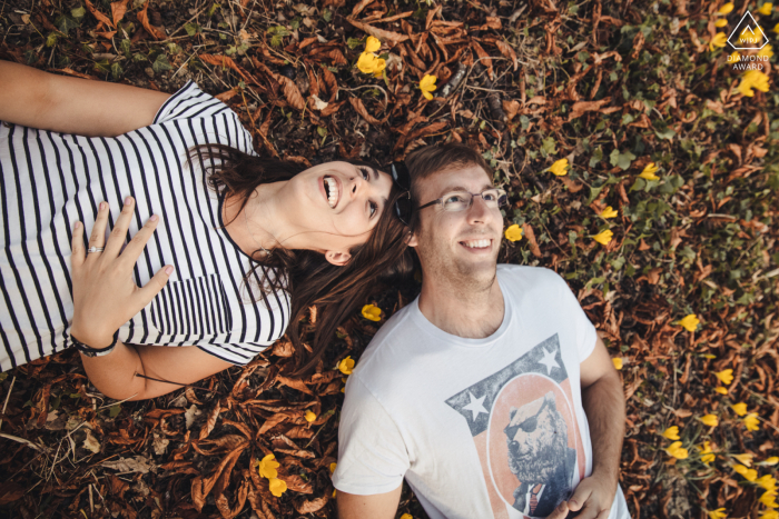 Séance photo de couple ludique dans le Gers alors qu'ils rient allongés dans l'herbe