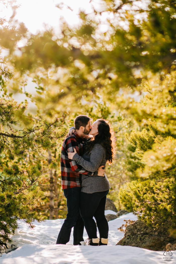 Golden Gate Canyon State Park pre - wed image with the Couple kissing in the trees with winter snow on the ground