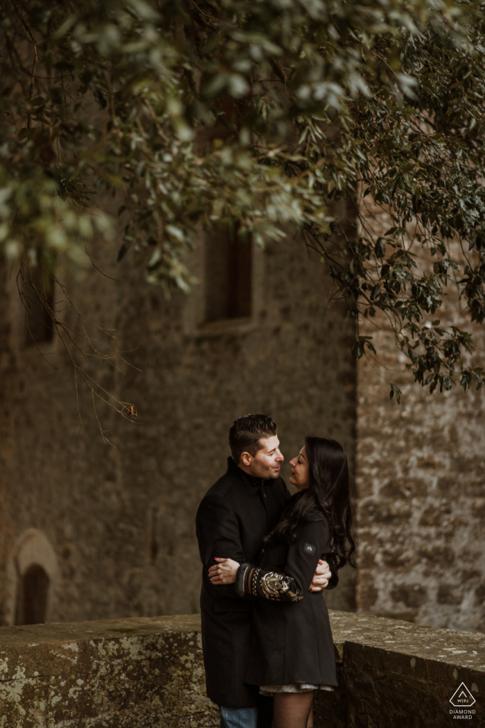 Ritratto di coppia di Siena prematrimoniale a Villa La Torre con i muri in pietra e gli alberi in alto