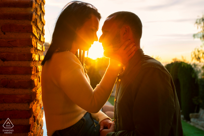 La Iruela pre - wed image by the brick column with a warm sunset behind their kiss