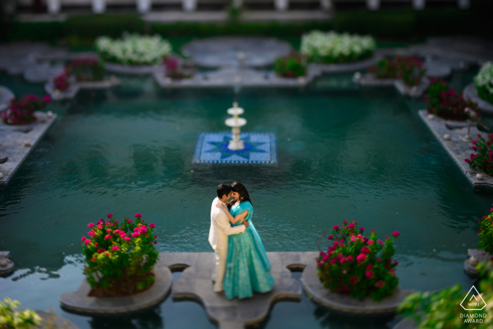 Sessione di foto di fidanzamento di coppia di Udaipur al Taj Lake Palace da un angolo alto sopra le piscine d'acqua con piante