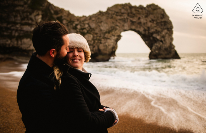 Portrait pré-mariage couple Dorset au bord de l'eau avec la gigantesque arche naturelle