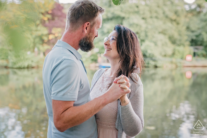 Casal de Witten Ruhrgebiet pré-casamento no lago com reflexos de árvores verdes