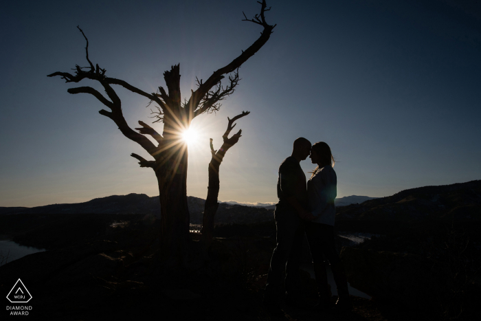 Retrato da silhueta de noivado do casal de Fort Collins com o sol poente olhando para as Montanhas Rochosas